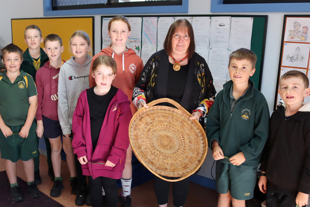 Aunty Royleen proudly shows students a woven dish used to serve food.