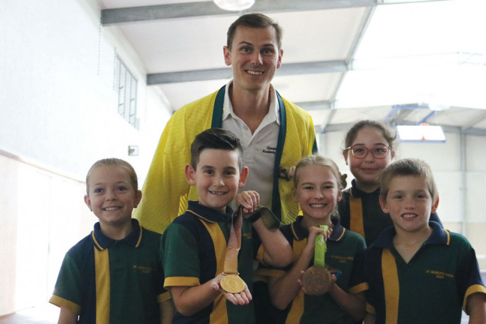 Dane Bird-Smith shows his Commonwealth and Olympic medals to students Abby, Nate, Arabella, Jennifer and Ace.