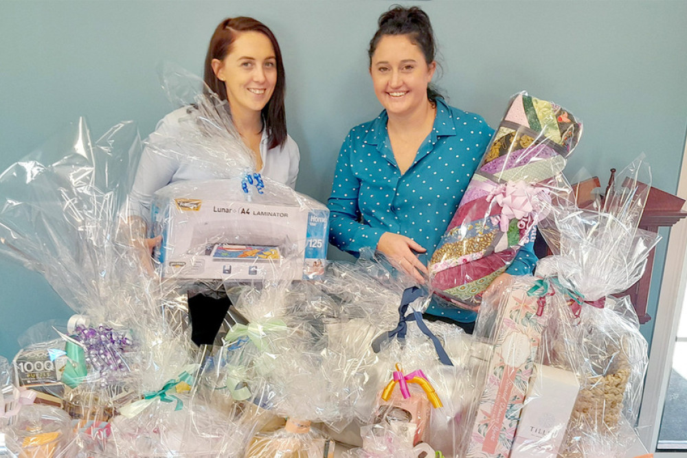 Administration and Events Assistant Amy Goldsmid and Volunteer Co-Ordinator Emma Hetherington display some of the multi-draw raffle prizes which will be up for grabs at this year’s Mother’s Day High Tea.