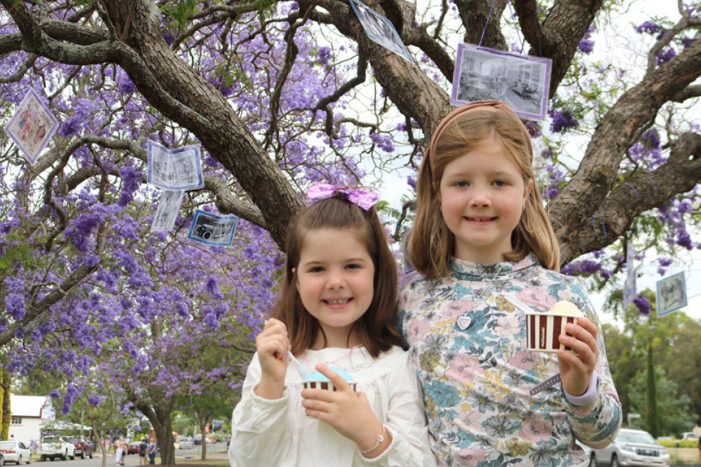 MacKenzie and Myllee enjoy snow cones under the jacaranda trees on Saturday.