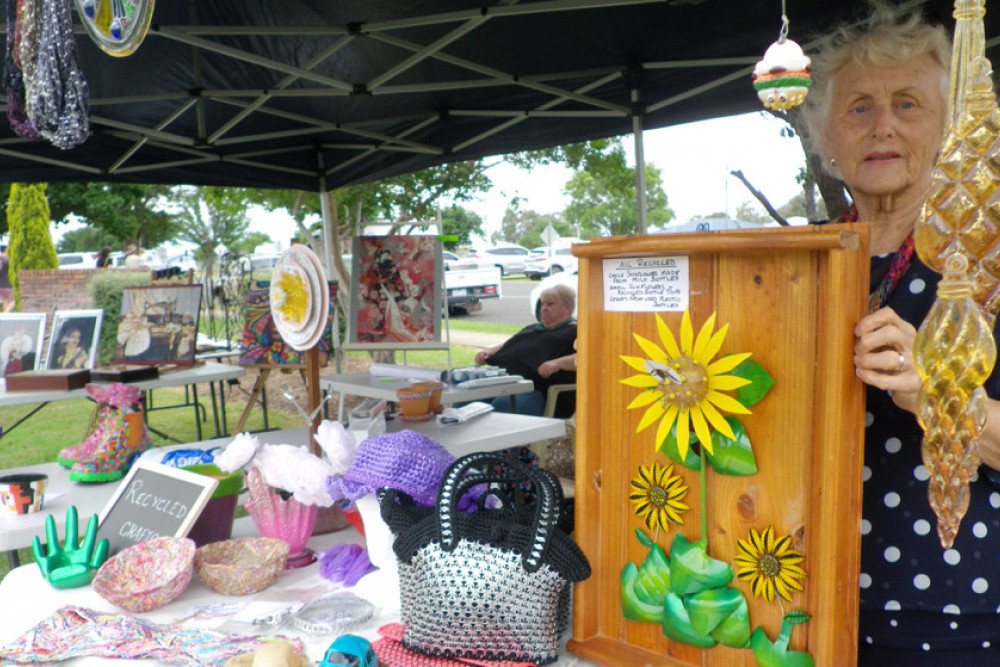 Marie Crispin presenting a sunflower made from milk bottles, plastic bottles and bottle tops and a handbag made using soft drink tin ring pulls.