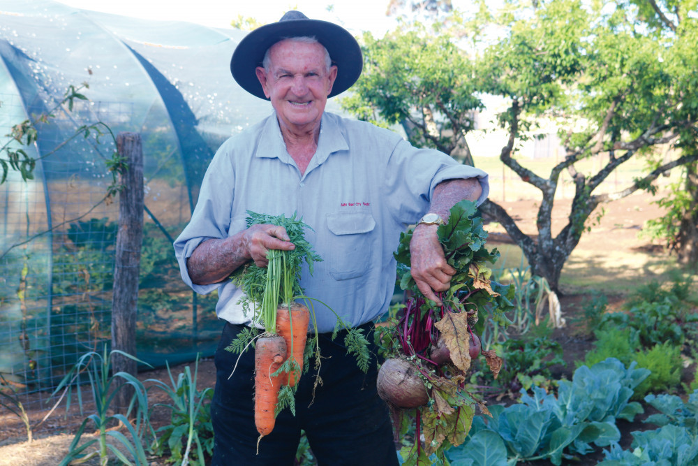 Merv Fowler proudly holds up the massive carrots and beetroots he has been growing this season in his spectacular vegetable garden.