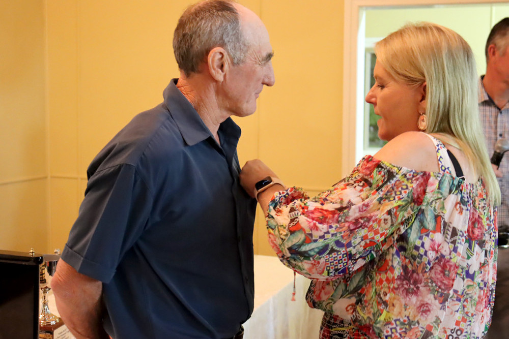 Wattles Club President Amanda O’Halloran attaches the Warriors’ 61st Life Membership badge to the chest of an emotional Neil Wilson at the Club’s annual Banquet and Presentation Night held in Clifton last Saturday.