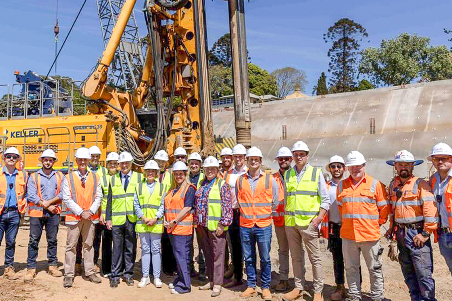 Staff from Darling Downs Health, the Department of Health, John Holland and Keller standing in front of the piling rig machine that is setting foundations for the new Toowoomba Hospital.