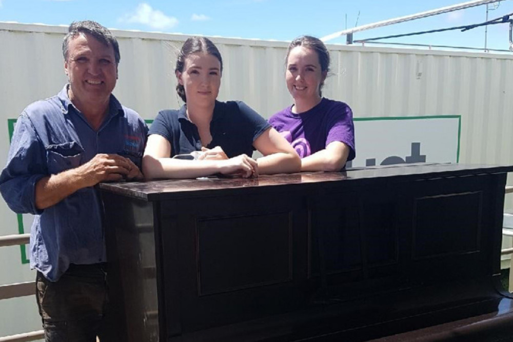 Clyde Wilkinson’s piano with (from left) his son Don and granddaughters Lexi and Tara.