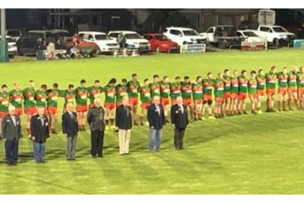 The A and B grade sides showing their respects during the Anzac Day ceremony before the A grade match.