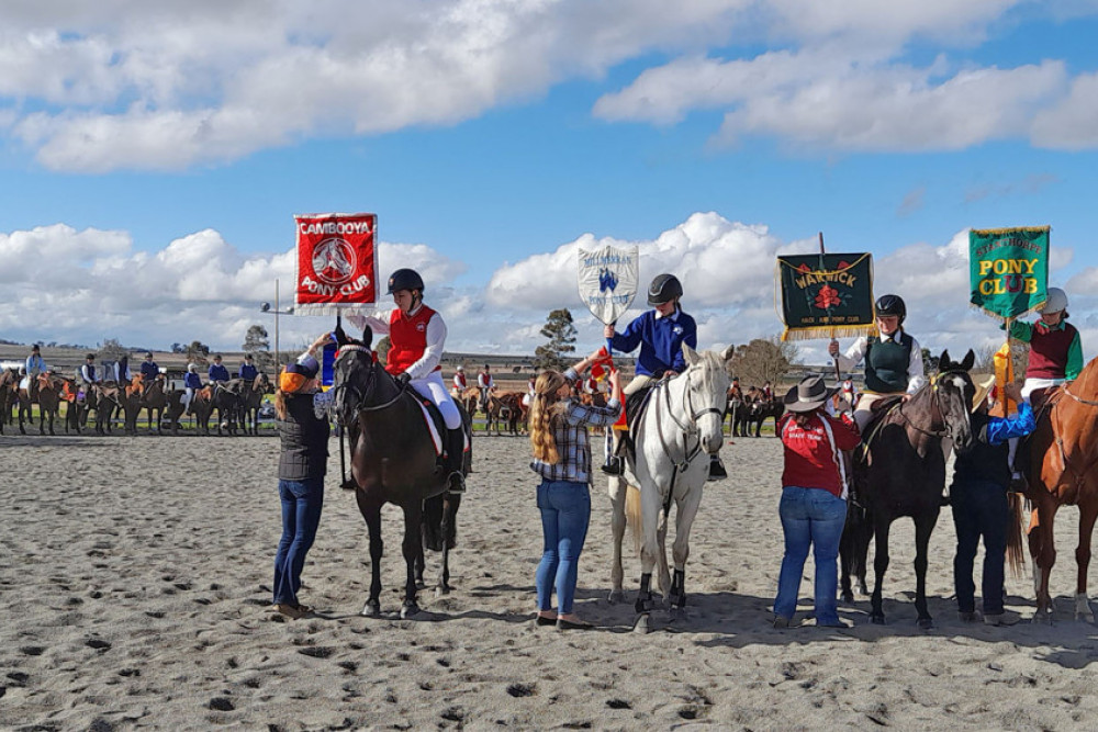 The gymkhana March Past winners and place getters with the judges sashing the flag bearer of the winning clubs. 1st Cambooya, 2nd Millmerran, 3rd Warwick and 4th Stanthorpe.