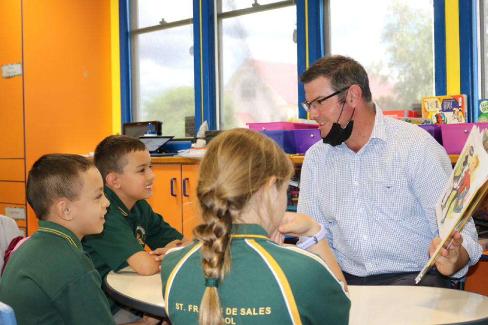 From left: Students Daniel, Xavier and Katherine are read a book by their new school principal, Brendan Redinger.