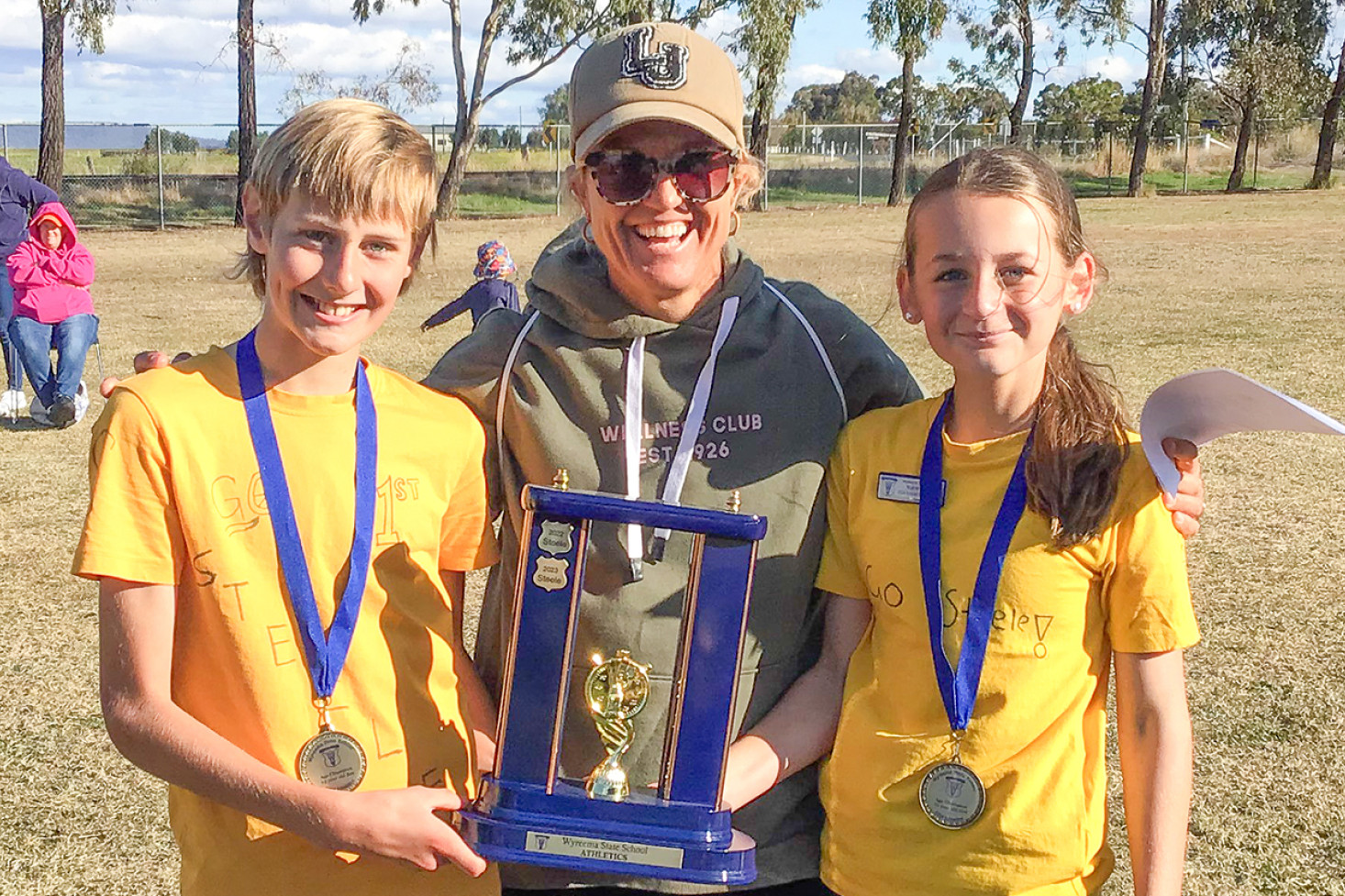 Steele, represented by sports captains Hayden and Kasari, was the 2024 Wyreema State School Athletics Carnival winning house. They are joined by HPE teacher Mrs Scott.
