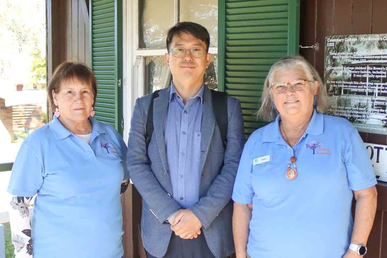 Standing on the verandah of Mrs Brown’s cottage are History Pittsworth volunteers Mary Sullivan and Barbara Walker during a tour of the Pioneer Village with Sung-Hak Yeo (centre) from the Paju Council.